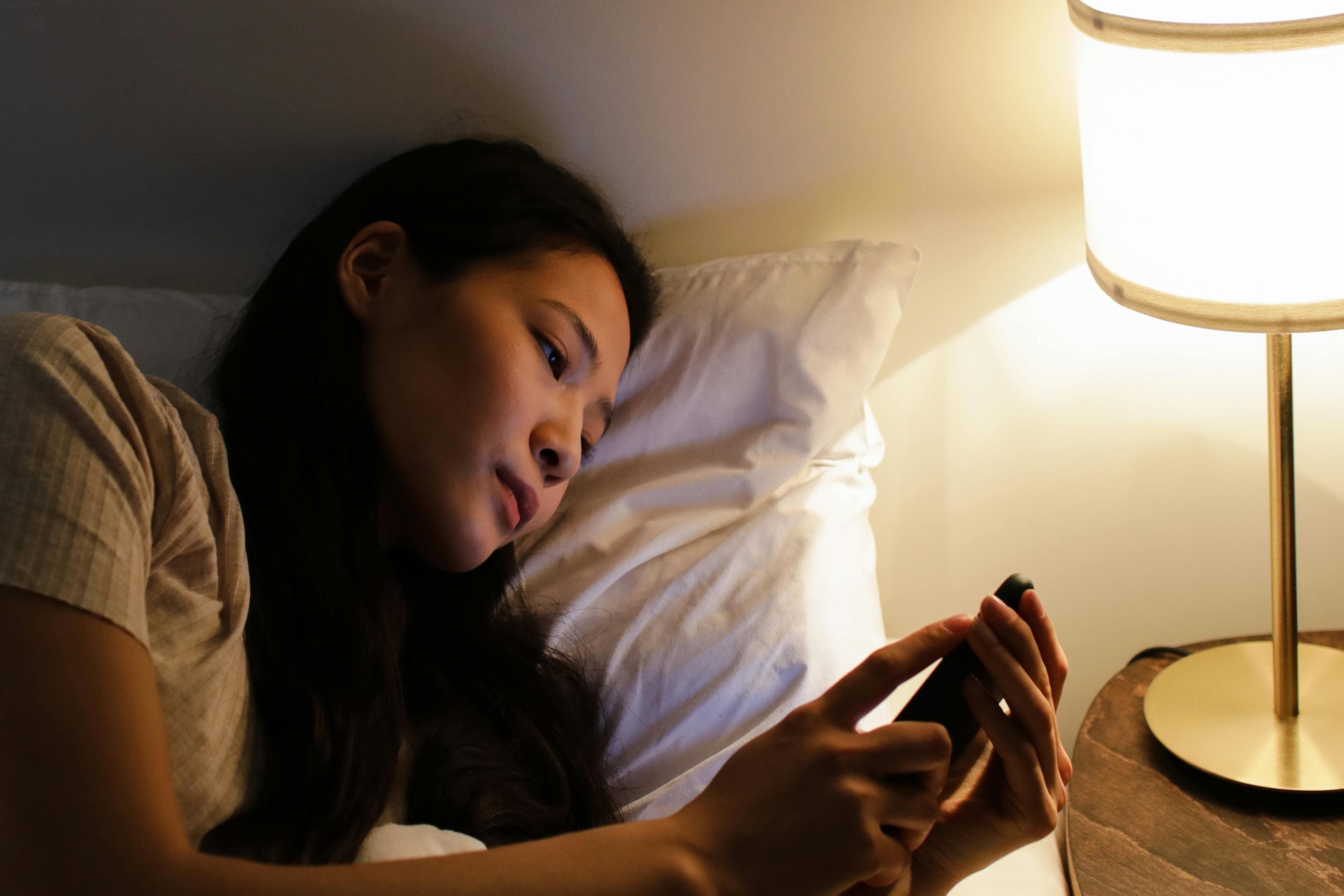 Ilustrasi wanita yang bermain handphone sebelum tidur. (Pexels) - Image