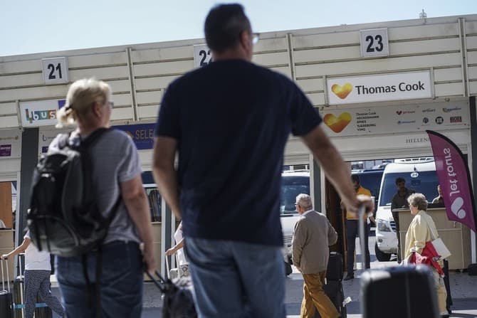 Tourists stand by a counter of Thomas Cook travel company at the Heraklion airport on the island of Crete on September 23, 2019. - British travel group Thomas Cook declared bankruptcy on September 23, 2019 after failing to reach a last-ditch rescue deal, - Image