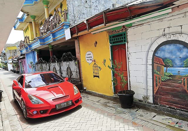 DAYA PIKAT BARU: Suasana Sememi Jaya Gang II kemarin (19/2). Beragam mural yang dikerjakan sejak Januari hingga awal Februari ini menambah kesan cerah. (Riana Setiawan/Jawa Pos) - Image