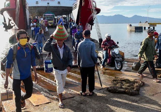 PULANG KAMPUNG ALIAS MUDIK: Para pemudik dari Bali menuju Pulau Jawa turun dari kapal feri di Pelabuhan Ketapang, Banyuwangi, Jawa Timur, kemarin (22/5). Mereka harus menjalani pemeriksaan kesehatan secara ketat sebelum dijemput satgas Covid-19 dari desa - Image