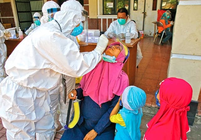 TAHAN SEBENTAR YA, BU: Nurmalita, ibu hamil 23 minggu, sedang menjalani swab test masal bersama keluarganya di Gelora Pancasila, Selasa (28/7). (Dipta Wahyu/Jawa Pos) - Image