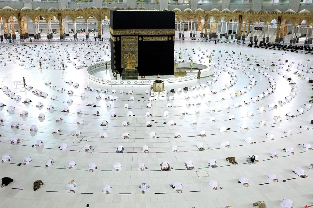 DIBUKA DENGAN PROKES KETAT: Jamaah menjalankan salat Tarawih di kompleks Kakbah, Makkah (13/4). (AFP) - Image