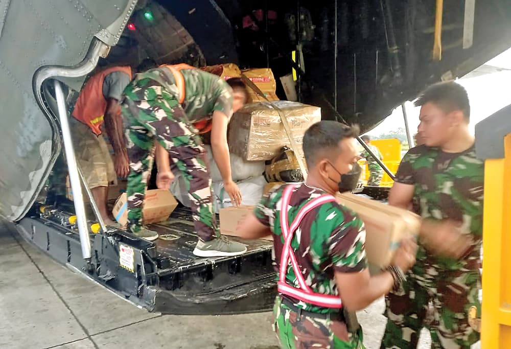 SUPLAI KE INDONESIA TIMUR: Personel TNI-AU menurunkan muatan berisi minyak goreng yang akan didistribusikan ke masyarakat Papua kemarin. (DISPENAU) - Image