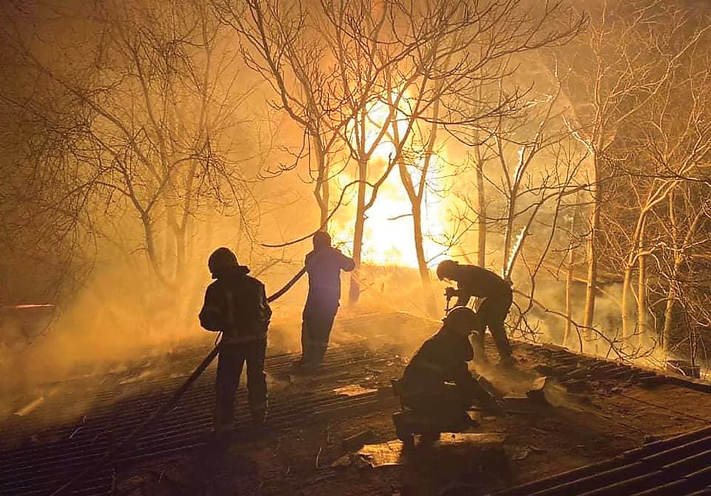 MASIH MEMBARA: Petugas berusaha memadamkan api yang membakar sebuah gudang di Mykolaiv, Ukraina, yang dipicu serangan Rusia (22/3). (AFP) - Image