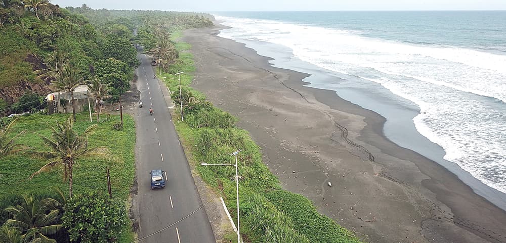 SEKALIGUS WISATA: Foto udara kendaraan yang melintas di Jalan Raya Ciparanti, Pangandaran, Jawa Barat (14/4). Jalur lintas pantai selatan Jawa ini adalah jalur alternatif mudik. (SALMAN TOYIBI/JAWA POS) - Image