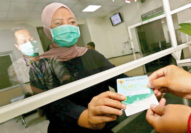 BEBAS BIAYA: Warga menunjukkan KTP dan Kartu BPJS Kesehatan untuk mendapatkan layanan kesehatan di RS dr M. Soewandhie, Sabtu (13/8). (Robertus Risky/Jawa Pos) - Image